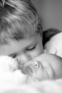 a woman holding a baby in her arms and kissing it's face with the other hand