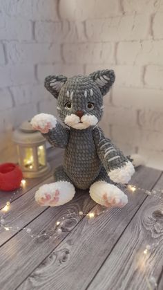 a stuffed animal cat sitting on top of a wooden table next to some candles and lights