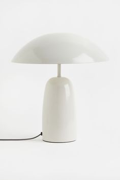 a white table lamp with a black cord attached to it's base on a white background