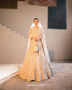 a woman in a white gown and veil standing on a stage with her hands behind her back