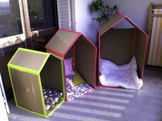 three cardboard houses sitting next to each other on top of a floor in front of a window