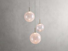 three clear glass globes hanging from a ceiling fixture in a room with concrete walls