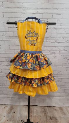 a yellow apron on a mannequin with flowers and the words hello kitty written on it