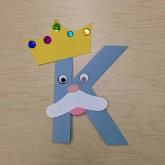 the letter k is made out of paper and has a crown on top of it