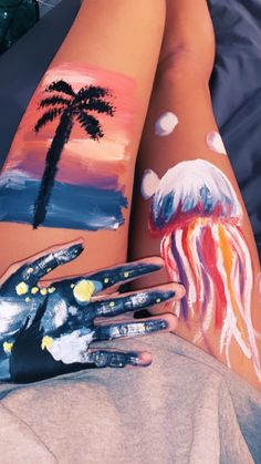 two people with painted hands and body art on their legs, one holding a jellyfish