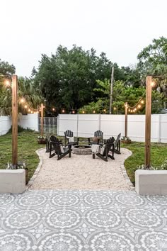 an outdoor seating area with chairs and lights on the trees in the back yard is lit up by string lights