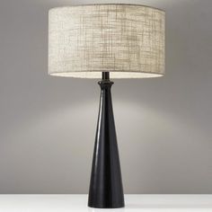 a black table lamp with a white shade on the base and a beige linen lampshade