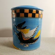 a blue and yellow ceramic container with an image of a cat on it's side