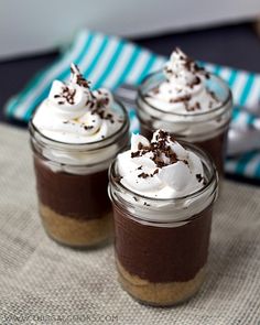 three desserts in glass jars with whipped cream and chocolate shaving on the top