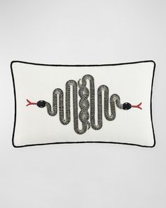 a white pillow with black and red embroidered snake on it