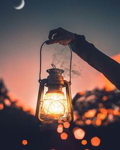 a person holding a lantern with the moon in the background