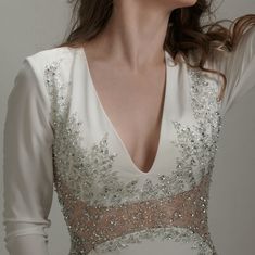 a woman wearing a white dress with silver sequins on it's shoulders