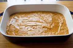 a white dish filled with brown sauce on top of a wooden table