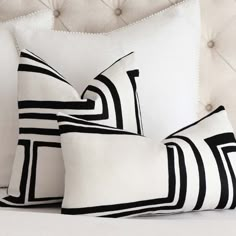 three black and white pillows sitting on top of a bed