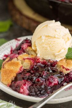 a close up of a plate of food with ice cream on top and berries in the background