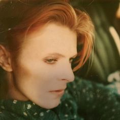 a woman with red hair and green shirt sitting in a car looking at the camera