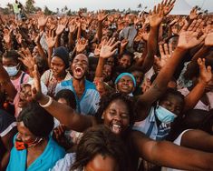 a large group of people with their hands in the air