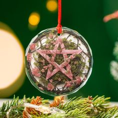 a glass ornament with pink stars hanging from it's side on a christmas tree