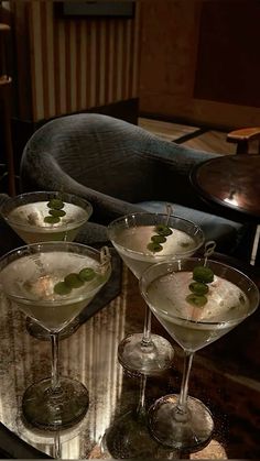 three martini glasses filled with white wine and garnished with green leaves