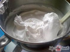 a metal bowl filled with whipped cream on top of a stove