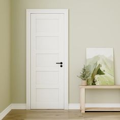 an empty room with a white door and wooden table in front of it, on a hard wood floor