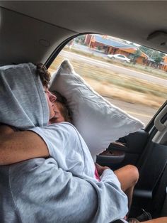 a man sleeping in the back seat of a car with his head up on a pillow