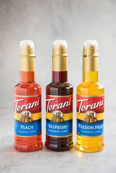 two bottles of torani raspberry and passion fruit syrup on a white surface