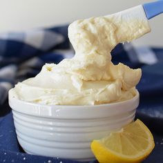 a small bowl filled with whipped cream next to a slice of lemon on a blue and white checkered cloth