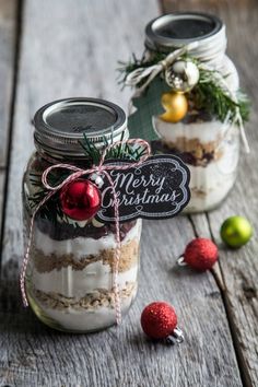 two mason jars filled with food on top of a wooden table next to christmas decorations