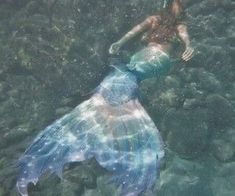 a woman is floating in the water near rocks