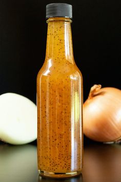 a glass bottle filled with mustard next to an onion