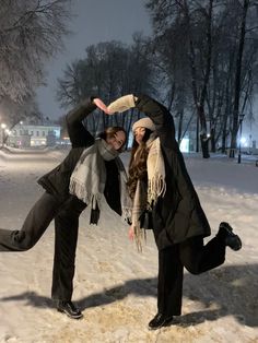 two people standing in the snow with their arms around each other and one person doing a handstand