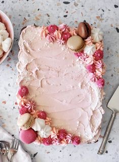 a pink frosted cake sitting on top of a table