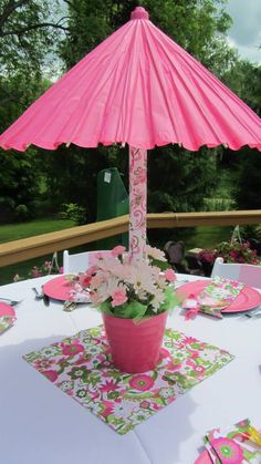 a pink umbrella sitting on top of a table with plates and napkins around it