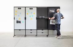 a man standing in front of two refrigerators with sticky notes on the doors and drawers