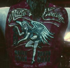 the back of a woman's leather jacket with an image of a winged demon on it