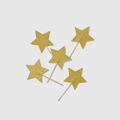 four gold glitter stars on top of each other with toothpicks in the middle