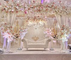 a white couch sitting under a chandelier covered in flowers