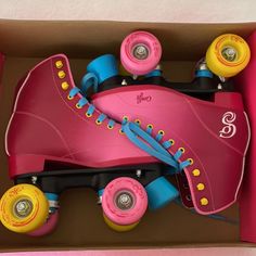 pink roller skates with yellow and blue wheels in a cardboard box on the floor