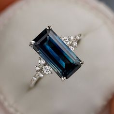 a blue and white diamond ring sitting on top of a cloth