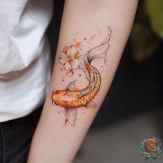 a woman's arm with a goldfish and flower tattoo on the left forearm