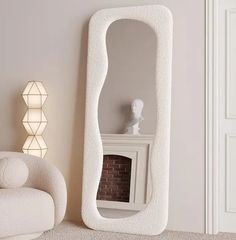 a large white mirror sitting next to a fireplace