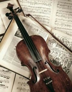 an old violin laying on top of music sheets