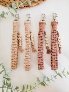 three keychains with tassels hanging from them on a table next to plants