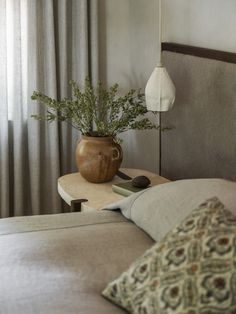 a bed with pillows and a vase on top of it