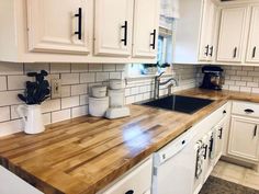 a kitchen with white cabinets and wooden counter tops