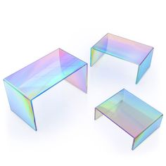 three glass tables sitting next to each other on top of a white surface with iridescent colors