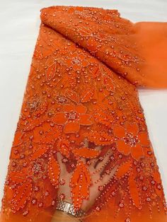 an orange scarf with beading on it and a hand in the middle of it