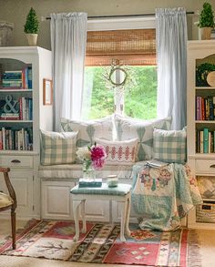 a living room filled with furniture and bookshelves next to a window covered in curtains