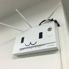 a white box with two antennas attached to it's face and smiling eyes on the wall